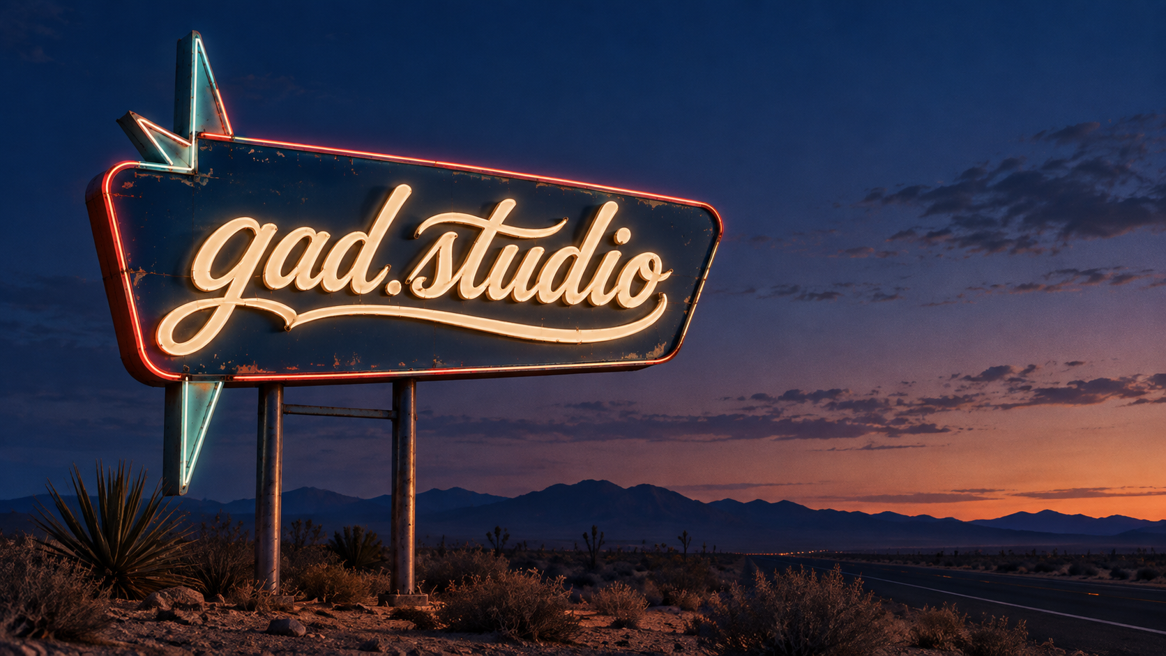 Et lysende gad.studio-skilt ved en vej i solnedgangen